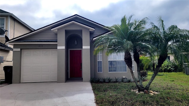 ranch-style house featuring concrete driveway, a front lawn, an attached garage, and stucco siding