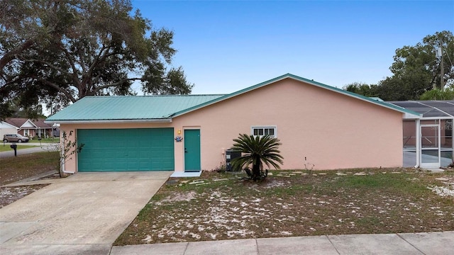 ranch-style home with driveway, a garage, metal roof, a lanai, and stucco siding