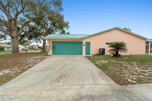 view of front of home featuring a garage, concrete driveway, metal roof, cooling unit, and stucco siding