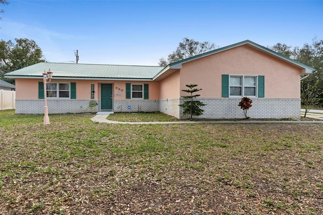 single story home with a front yard, brick siding, metal roof, and stucco siding