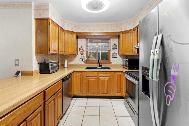 kitchen with light countertops, brown cabinets, a sink, and stainless steel appliances