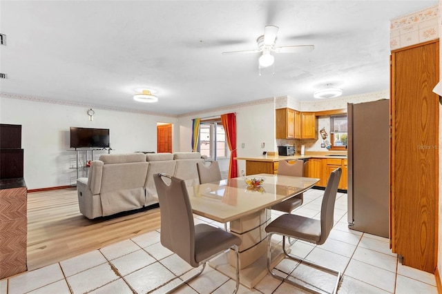 dining space with baseboards, a ceiling fan, light wood-style flooring, and a healthy amount of sunlight