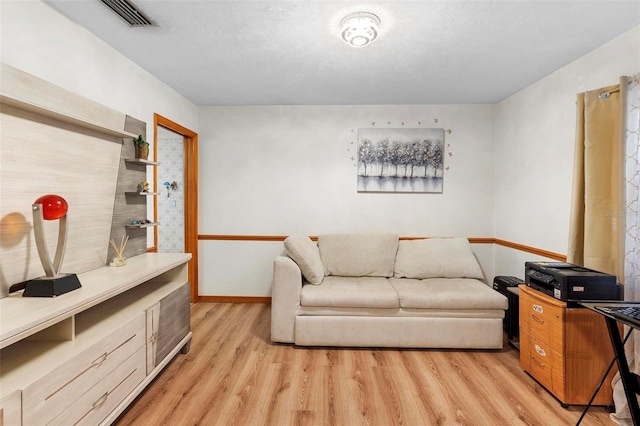 living area featuring light wood finished floors, baseboards, and visible vents