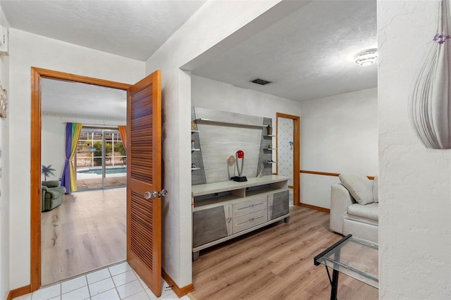 living area with light wood-style floors, baseboards, visible vents, and a textured ceiling