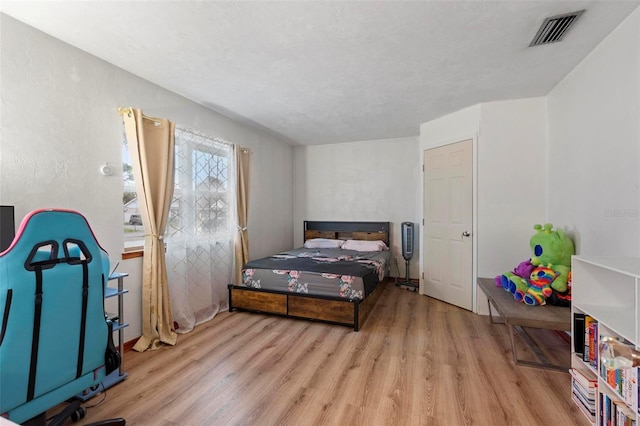 bedroom with a textured ceiling, visible vents, and light wood-style floors