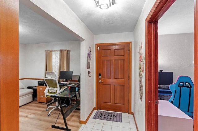 foyer with light wood-type flooring, a textured ceiling, and baseboards