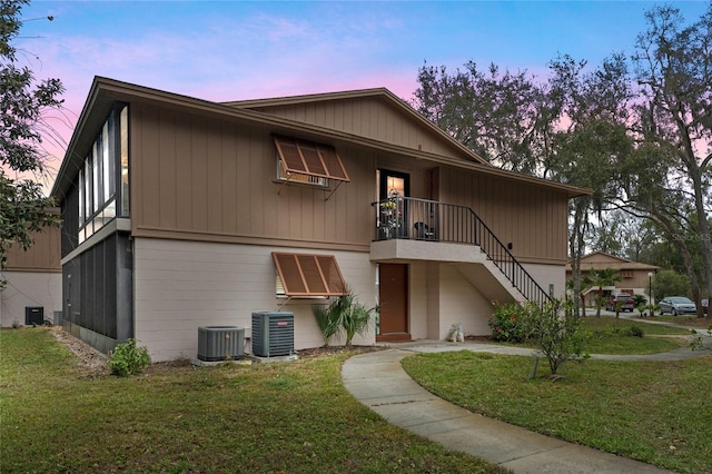 view of front of house with a front lawn, stairway, and central air condition unit