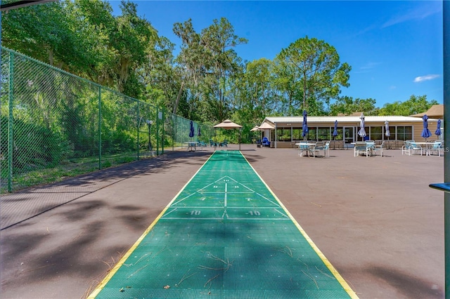 view of property's community featuring shuffleboard and fence