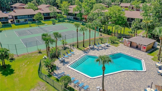 community pool with a patio area, fence, and a residential view