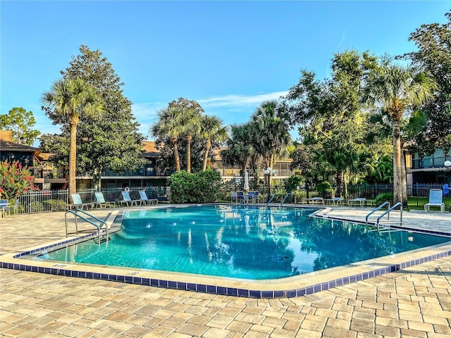 community pool with fence and a patio