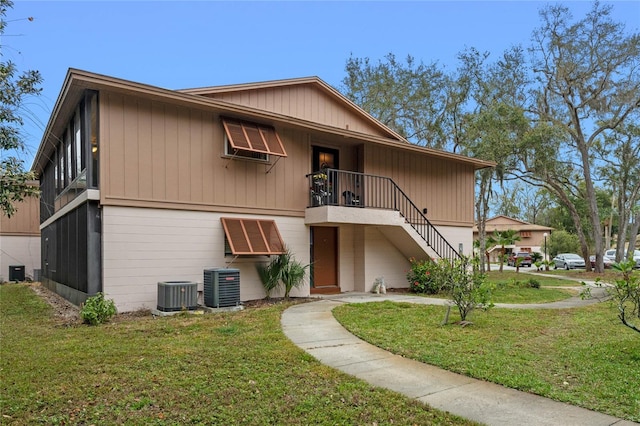 view of front of home with a front yard, central AC, and stairs