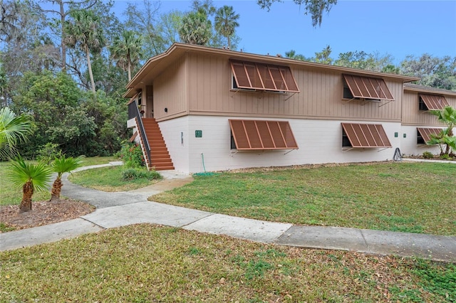 view of front of house featuring stairs and a front yard