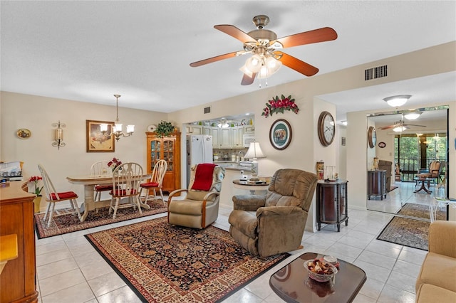 living area with ceiling fan with notable chandelier, visible vents, a textured ceiling, and light tile patterned floors