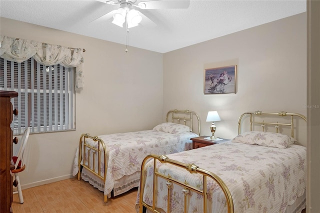 bedroom featuring light wood-style floors, a textured ceiling, baseboards, and a ceiling fan