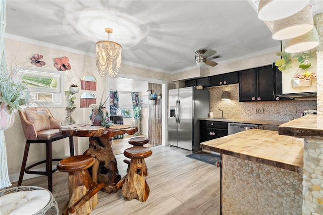 kitchen with crown molding, tasteful backsplash, appliances with stainless steel finishes, ceiling fan, and wood counters