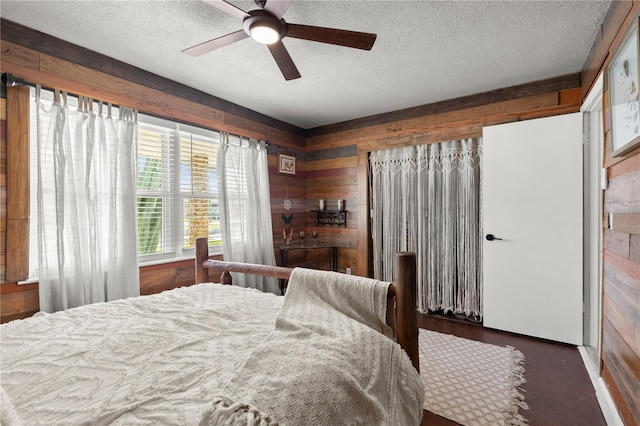 bedroom featuring wooden walls, a textured ceiling, and a ceiling fan