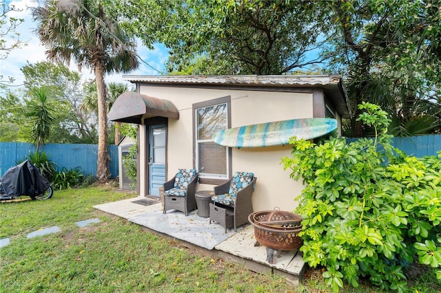 back of property featuring an outdoor fire pit, an outdoor structure, fence, and stucco siding