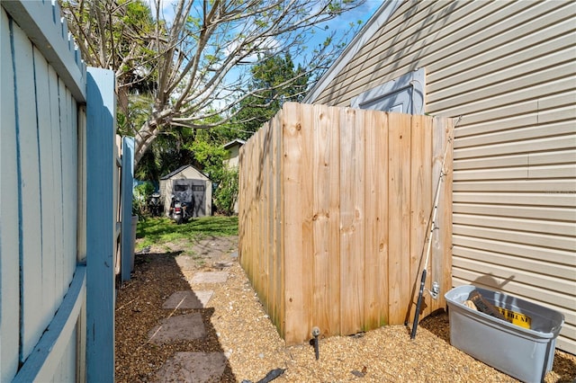 exterior space with a storage shed, an outbuilding, and fence