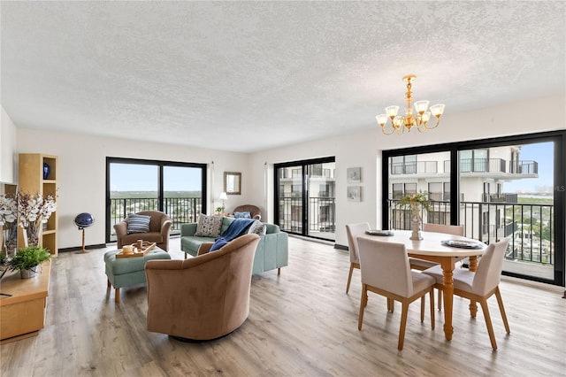 living area featuring a textured ceiling, light wood finished floors, baseboards, and a notable chandelier