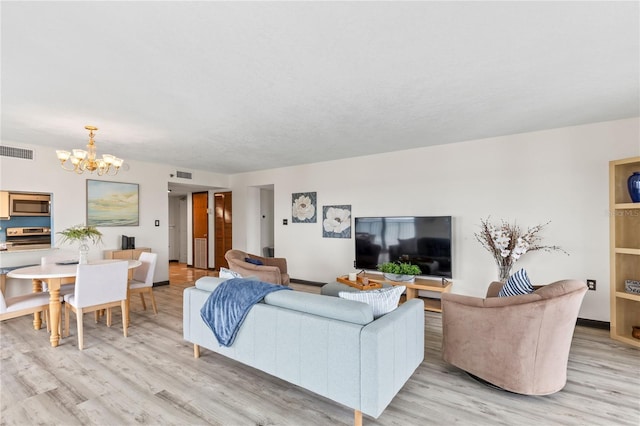 living area with light wood-style flooring, visible vents, and a notable chandelier