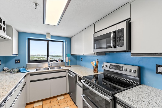 kitchen with stainless steel appliances, white cabinetry, a sink, and a textured ceiling