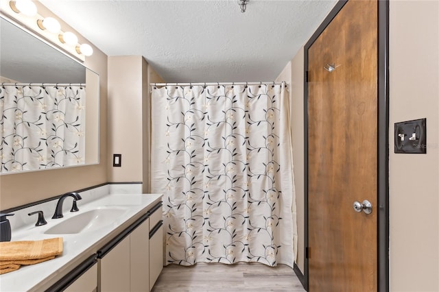 full bathroom featuring a shower with shower curtain, wood finished floors, a textured ceiling, and vanity