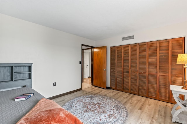 bedroom with light wood-style flooring, a closet, visible vents, and baseboards