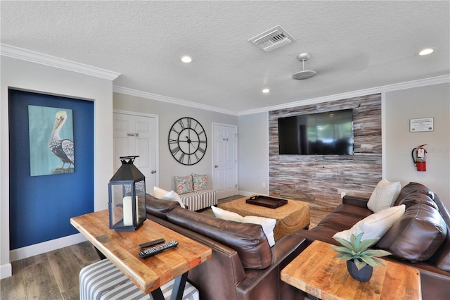 living room featuring a textured ceiling, an accent wall, wood finished floors, visible vents, and crown molding