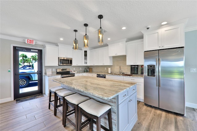 kitchen featuring pendant lighting, stainless steel appliances, glass insert cabinets, a kitchen island, and a kitchen bar