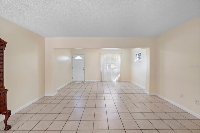 interior space featuring light tile patterned floors, baseboards, and a textured ceiling