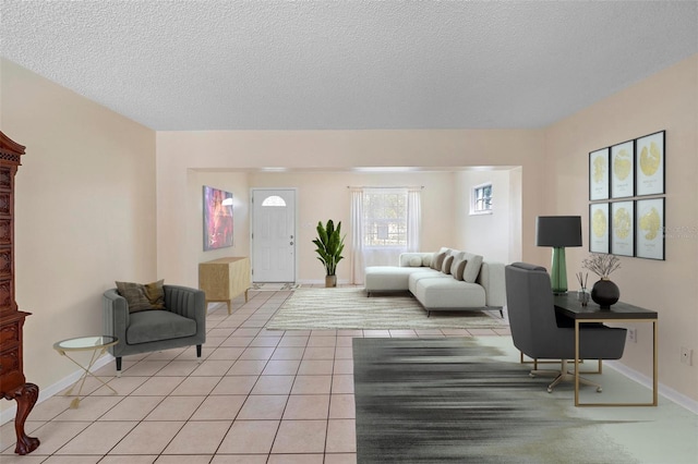 living area with baseboards, a textured ceiling, and light tile patterned floors