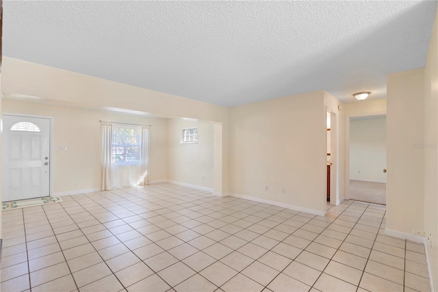 interior space with a textured ceiling, baseboards, and light tile patterned floors