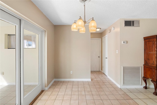 empty room featuring visible vents, a textured ceiling, a chandelier, and light tile patterned flooring