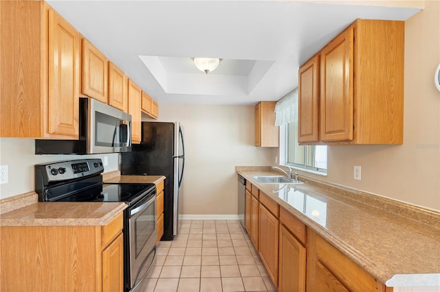 kitchen featuring stainless steel appliances, a tray ceiling, a sink, light tile patterned flooring, and light countertops