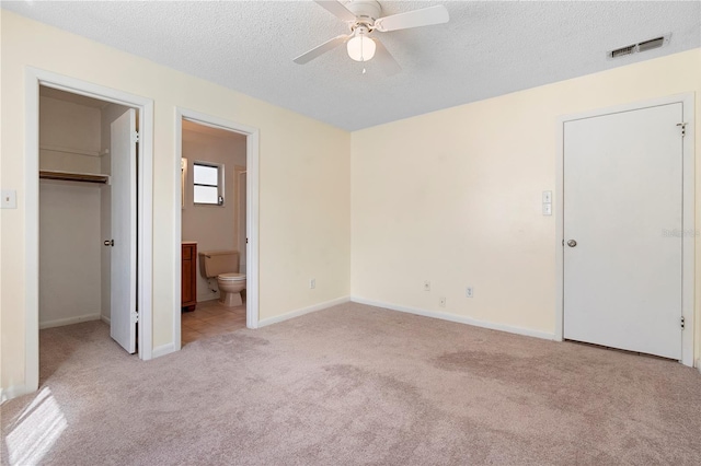 unfurnished bedroom featuring a spacious closet, carpet flooring, a textured ceiling, and visible vents