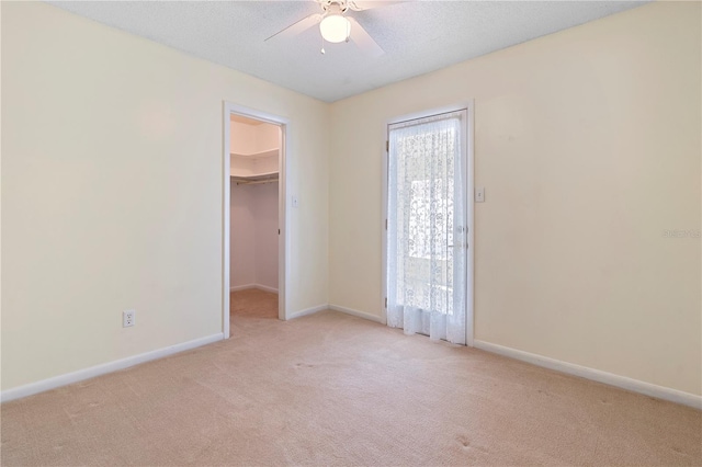 unfurnished bedroom featuring light colored carpet, baseboards, a spacious closet, and a closet