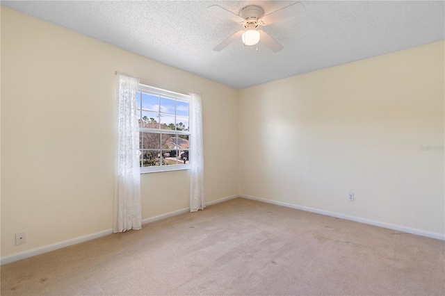 carpeted empty room with a textured ceiling, baseboards, and ceiling fan