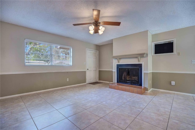 unfurnished living room featuring a textured ceiling, a fireplace, a ceiling fan, baseboards, and tile patterned floors