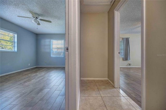 interior space with a textured ceiling, a ceiling fan, and a healthy amount of sunlight