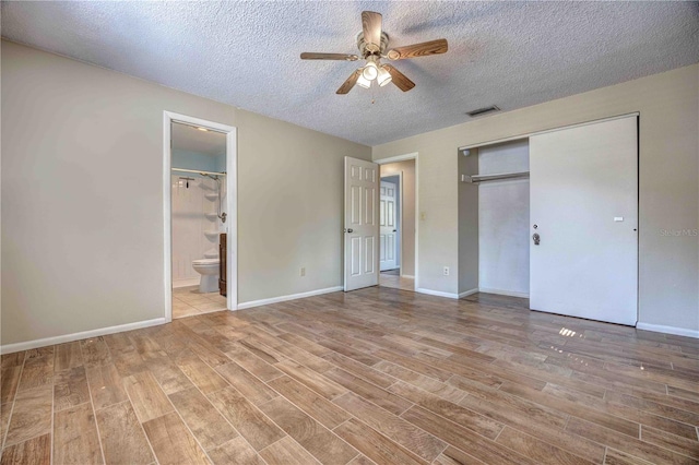 unfurnished bedroom featuring visible vents, connected bathroom, and light wood-style flooring