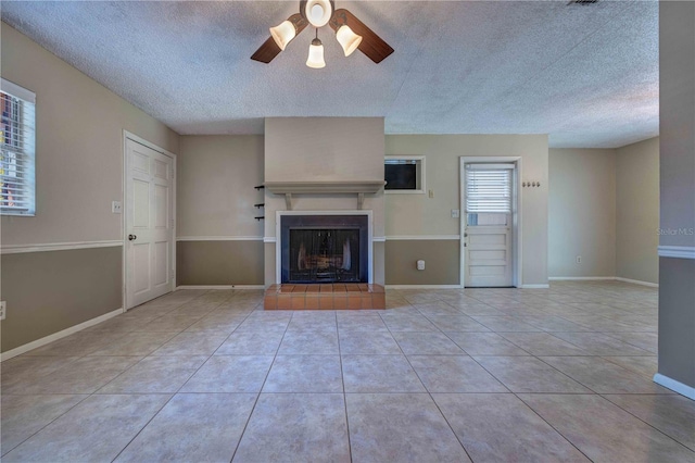 unfurnished living room featuring ceiling fan, a fireplace, baseboards, and tile patterned floors