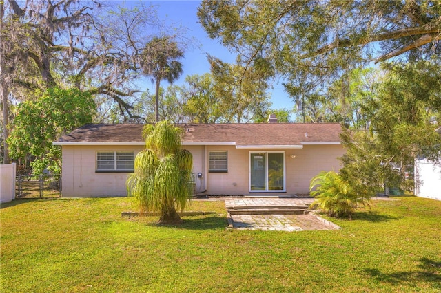 rear view of house with concrete block siding, a lawn, a patio area, and fence