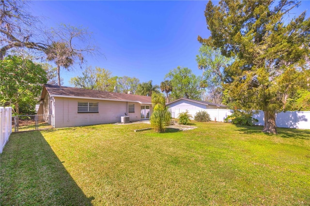 back of house with cooling unit, a fenced backyard, and a yard