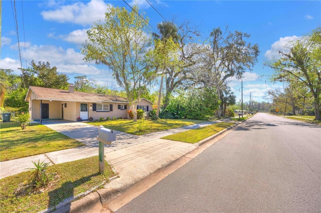 view of front of property featuring a chimney, a front yard, concrete driveway, and an attached carport