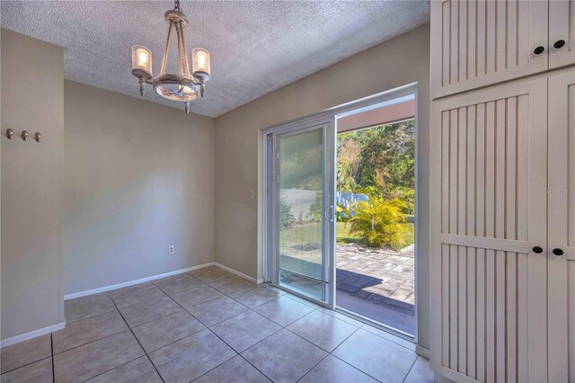 741 Greenway Pl, Daytona Beach, FL 32114 - unfurnished dining area with a chandelier, tile patterned floors, a textured ceiling, and baseboards