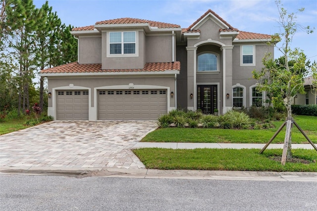 mediterranean / spanish-style home with a tile roof, a front lawn, decorative driveway, and stucco siding