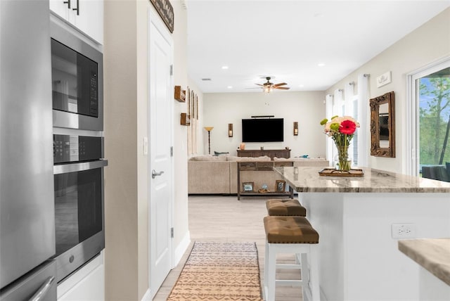 32924 Estate Garden Dr, Wesley Chapel, FL 33545 - kitchen featuring stainless steel appliances, open floor plan, white cabinets, ceiling fan, and a kitchen breakfast bar