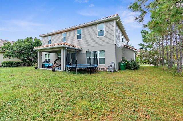 32924 Estate Garden Dr, Wesley Chapel, FL 33545 - rear view of property with stucco siding, a trampoline, and a yard