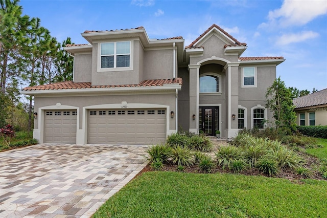 32924 Estate Garden Dr, Wesley Chapel, FL 33545 - mediterranean / spanish house featuring an attached garage, stucco siding, decorative driveway, and a tiled roof