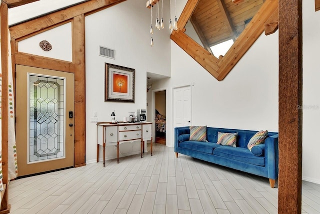 foyer entrance with baseboards, visible vents, light wood-style flooring, and lofted ceiling with beams